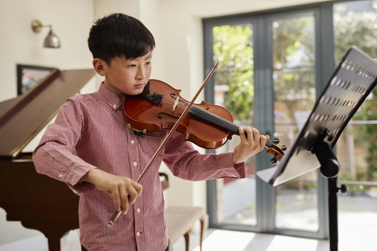 A young violinist practising at a music stand at home
